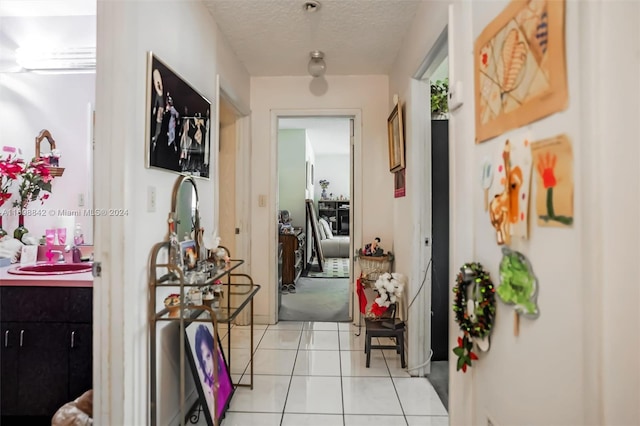 corridor featuring sink, light tile patterned floors, and a textured ceiling