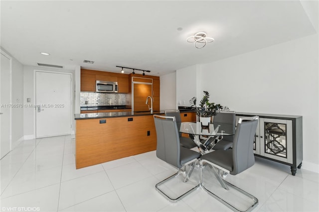 dining area with rail lighting, sink, and light tile patterned floors