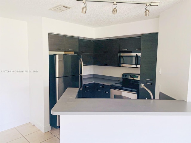 kitchen featuring stainless steel appliances, kitchen peninsula, a textured ceiling, track lighting, and light tile patterned flooring