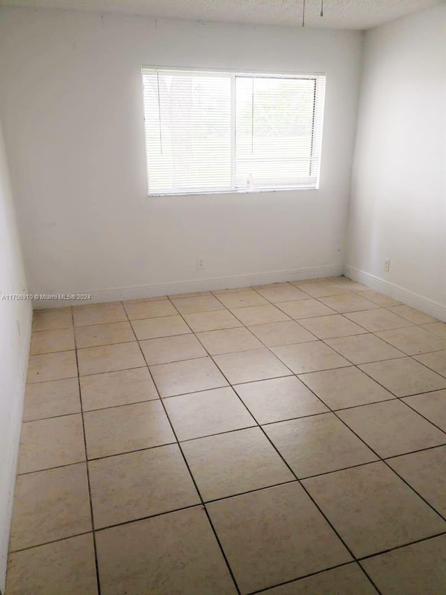 tiled empty room with a textured ceiling