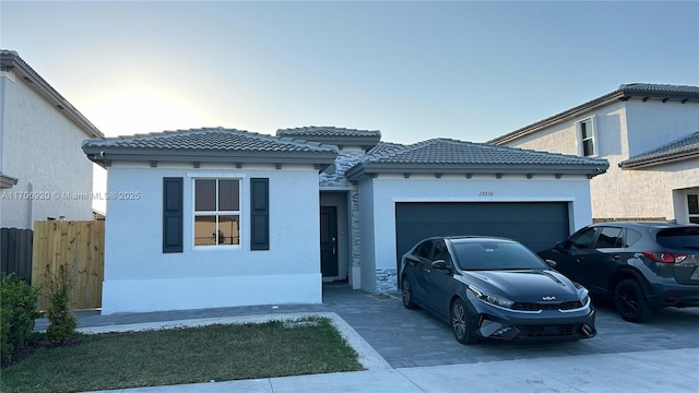 mediterranean / spanish-style home with stucco siding, an attached garage, and decorative driveway