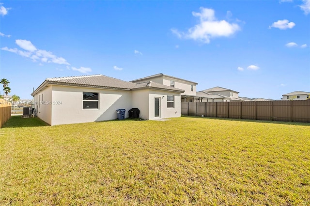 rear view of house with a lawn and central AC