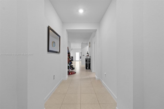 corridor with baseboards and light tile patterned flooring