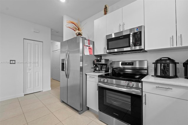 kitchen featuring light tile patterned floors, appliances with stainless steel finishes, white cabinetry, and light countertops