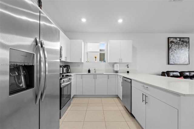 kitchen with a sink, stainless steel appliances, a peninsula, light tile patterned flooring, and light countertops