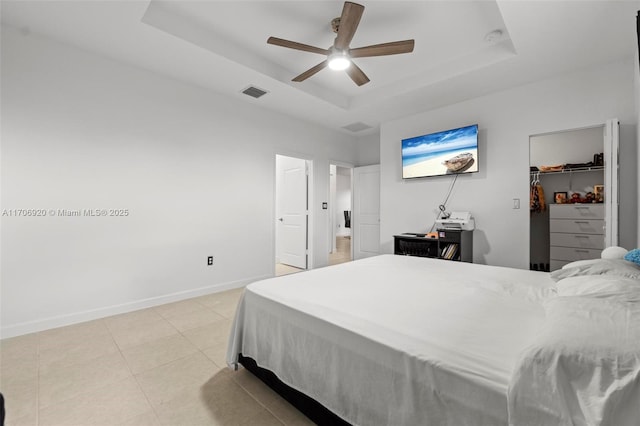 bedroom with visible vents, baseboards, light tile patterned flooring, a raised ceiling, and a spacious closet