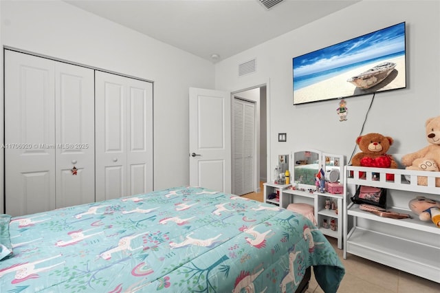 bedroom featuring tile patterned floors, visible vents, and a closet