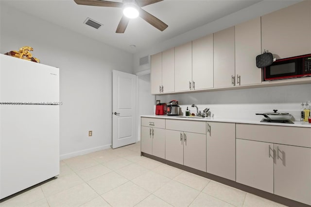 kitchen featuring light countertops, visible vents, freestanding refrigerator, and a sink