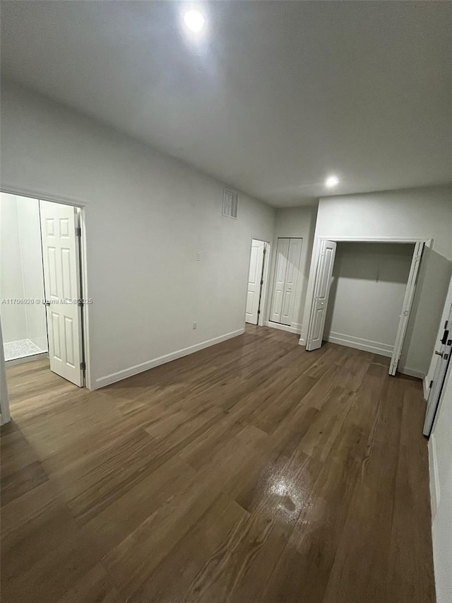 unfurnished bedroom with recessed lighting, baseboards, multiple closets, and dark wood-style flooring