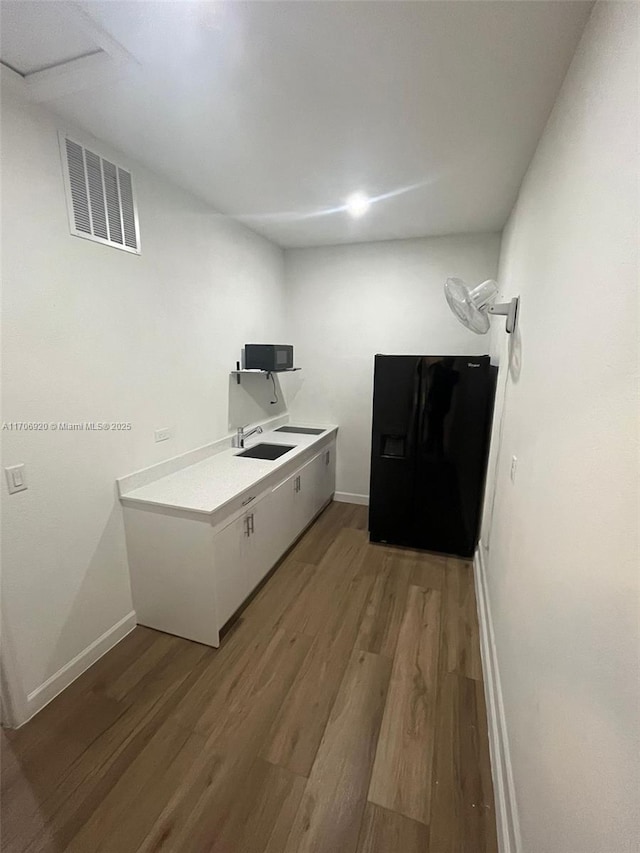 interior space with a sink, visible vents, baseboards, and light wood-style floors