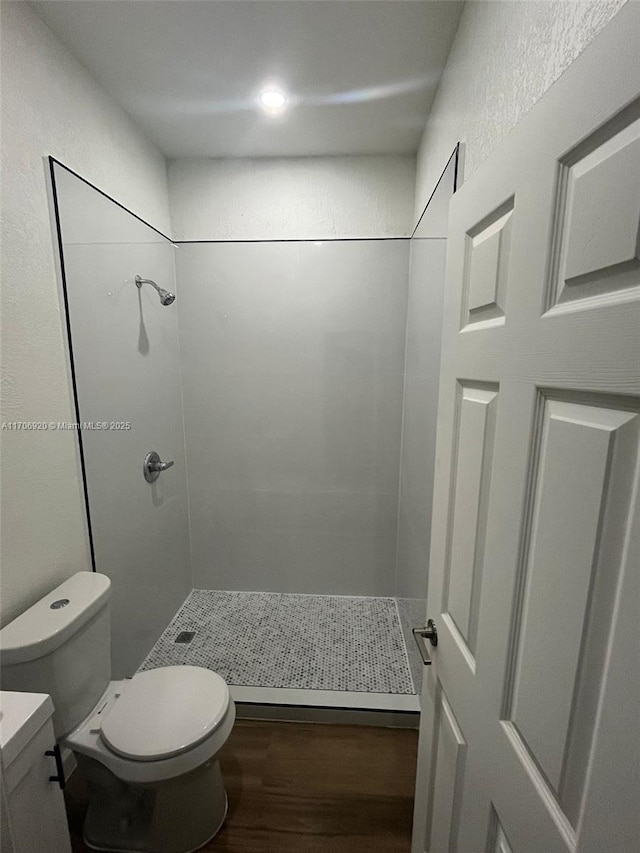 full bath with a stall shower, toilet, and wood finished floors