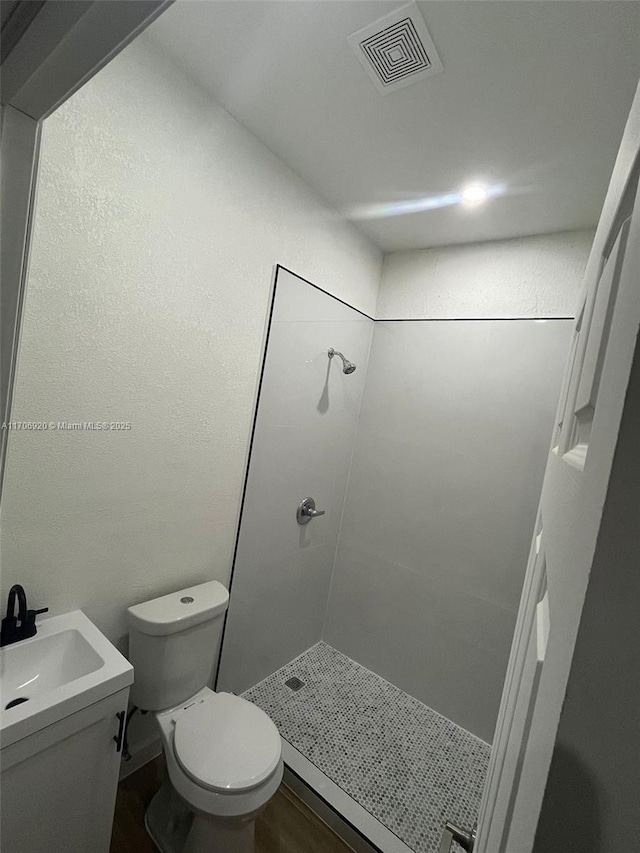 bathroom with vanity, toilet, visible vents, and a stall shower