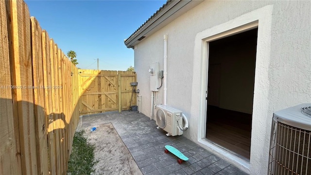 view of side of home with fence, central AC, ac unit, stucco siding, and a gate