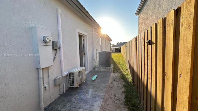 view of property exterior featuring central air condition unit, ac unit, fence, and stucco siding