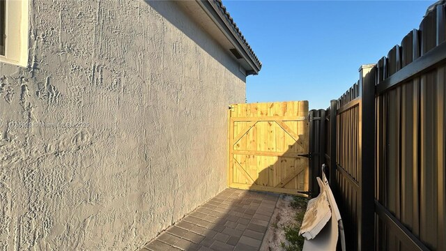 view of side of home featuring a gate, fence, and stucco siding