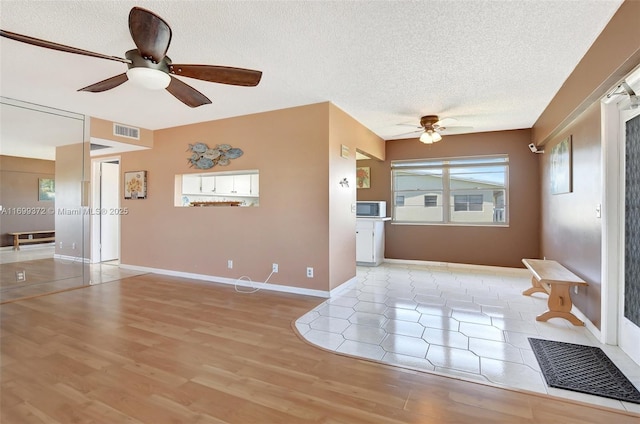 interior space with ceiling fan, light hardwood / wood-style flooring, and a textured ceiling