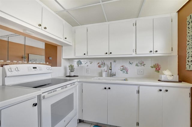 kitchen with white electric range oven, a sink, light countertops, white cabinets, and backsplash