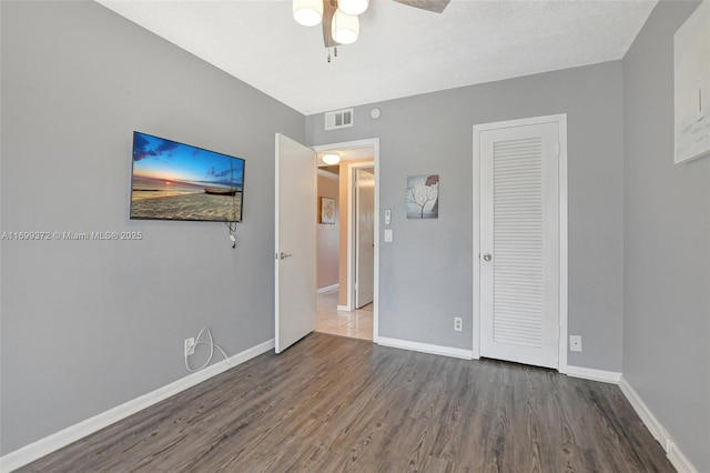 unfurnished bedroom featuring hardwood / wood-style floors, a closet, and ceiling fan