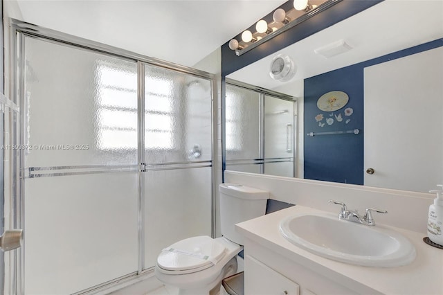 bathroom featuring vanity, toilet, and a shower with door