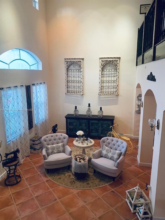 living area featuring a high ceiling and dark tile patterned floors