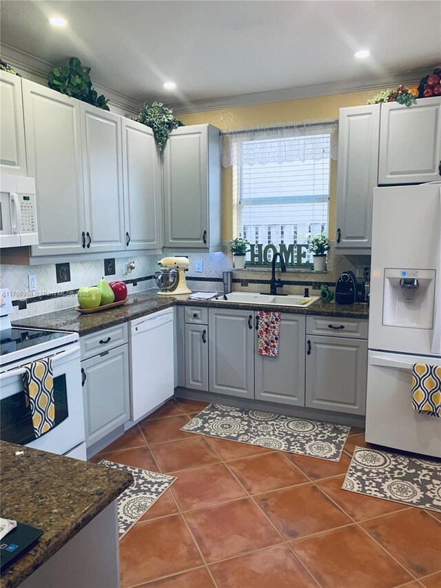 kitchen with white appliances, dark tile patterned floors, tasteful backsplash, sink, and gray cabinetry