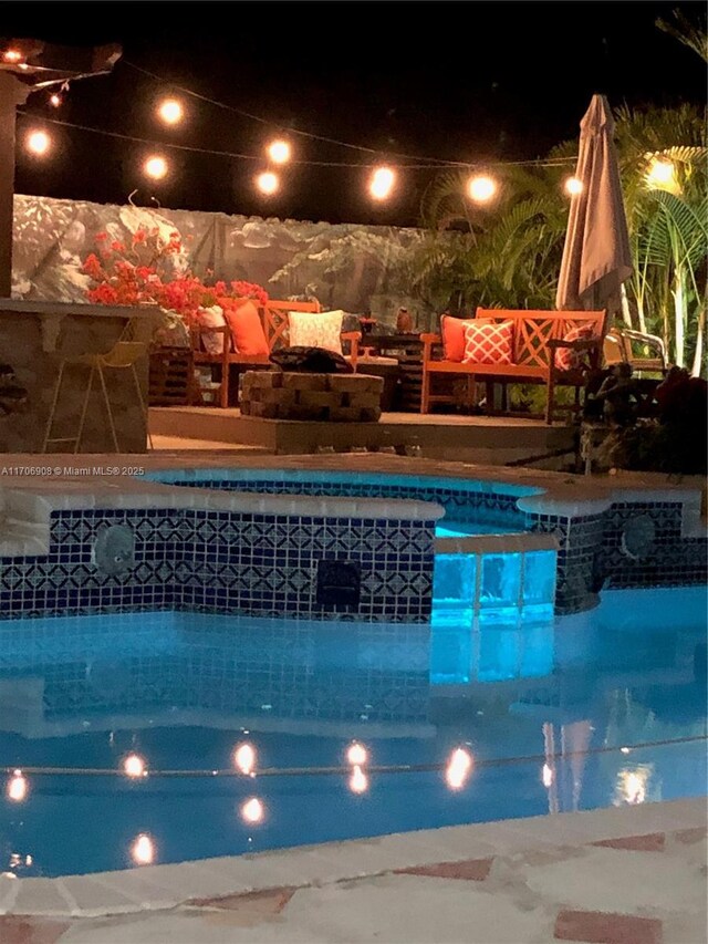 pool at twilight featuring an in ground hot tub and a patio area