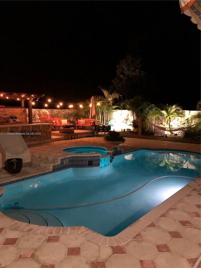 pool at twilight featuring a patio area and an in ground hot tub