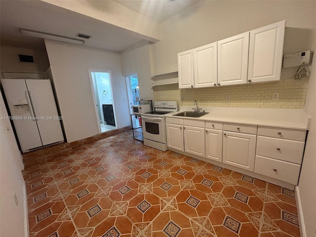 kitchen featuring dark tile patterned flooring, decorative backsplash, sink, white appliances, and white cabinets