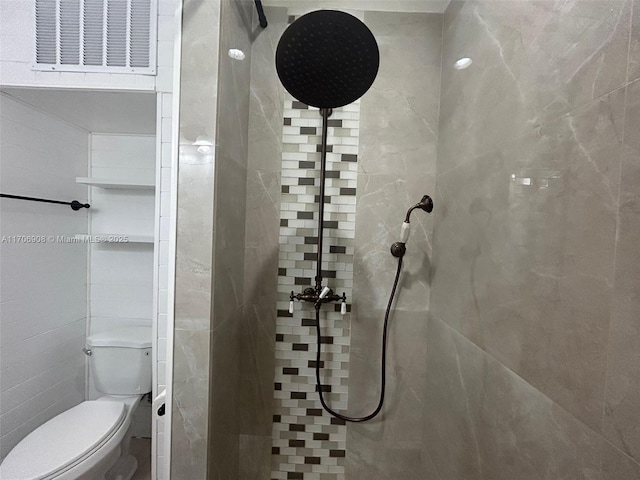 bathroom featuring toilet and a tile shower