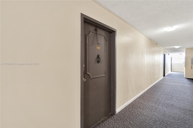 corridor with a textured ceiling and dark carpet