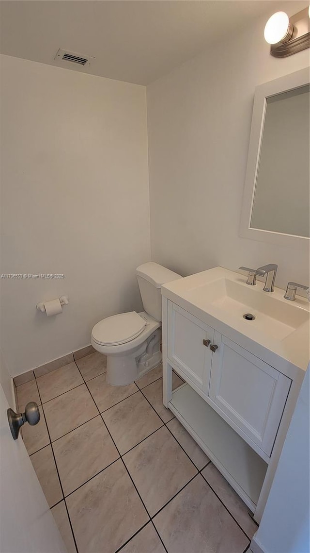 bathroom with toilet, vanity, and tile patterned flooring