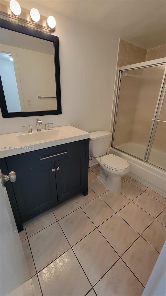 full bathroom featuring toilet, tile patterned floors, enclosed tub / shower combo, and vanity