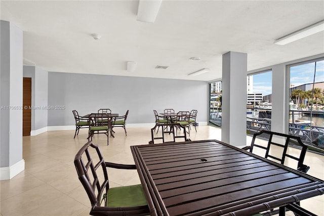 dining area featuring a water view, a wall of windows, and light tile patterned floors