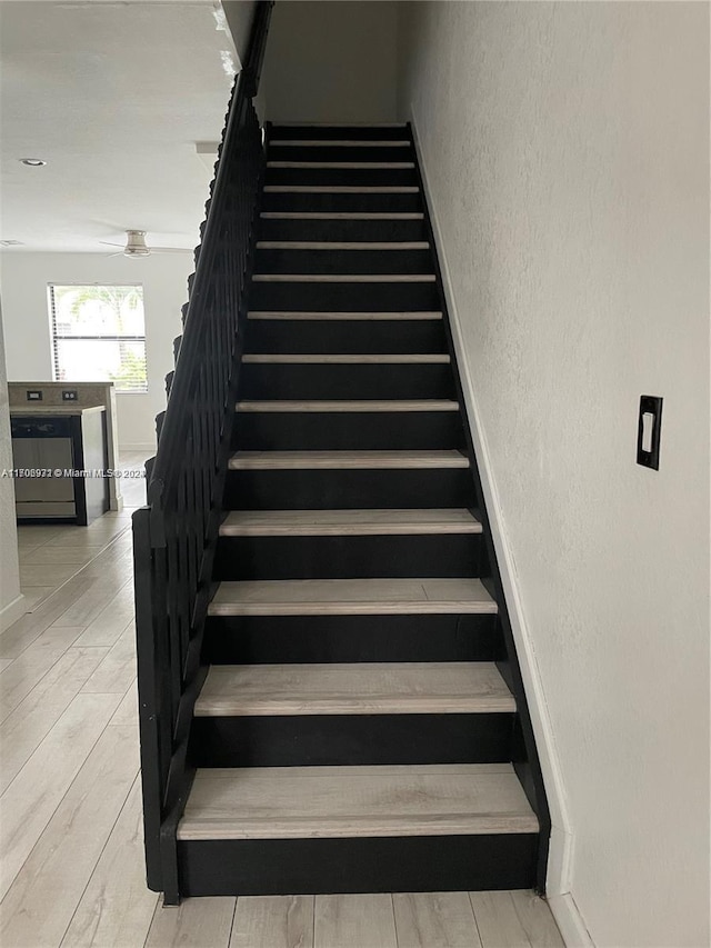 stairs with hardwood / wood-style flooring and ceiling fan