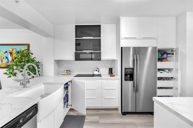 kitchen with tasteful backsplash, light stone counters, white cabinetry, and black appliances