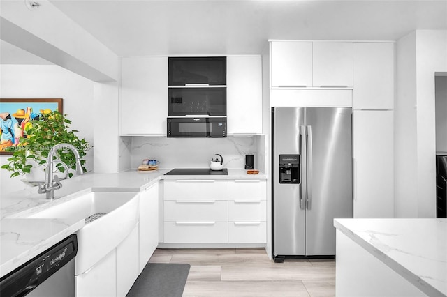 kitchen with decorative backsplash, light stone counters, white cabinets, and black appliances