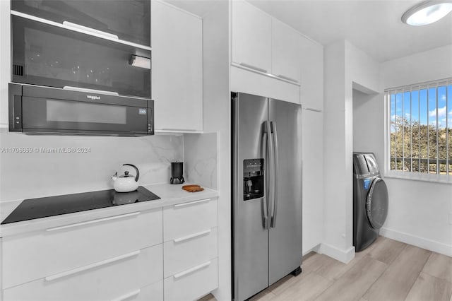 kitchen with tasteful backsplash, black appliances, light hardwood / wood-style flooring, washer / dryer, and white cabinetry