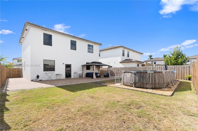 back of property with a gazebo, a patio area, a fenced in pool, and a yard