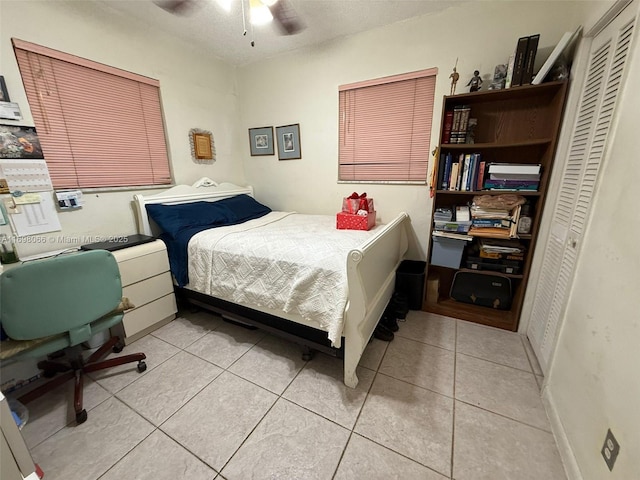 tiled bedroom featuring a textured ceiling, ceiling fan, and a closet