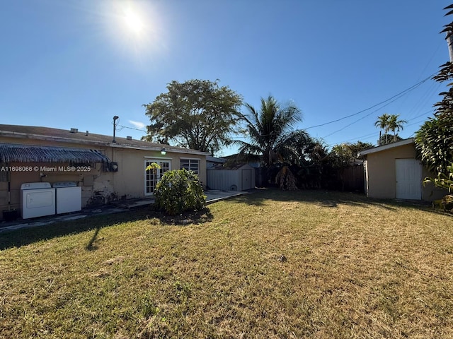 view of yard featuring washer and clothes dryer and a storage shed