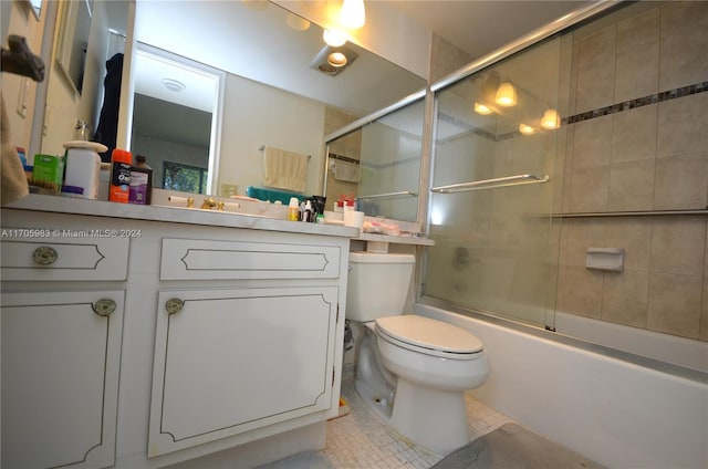 full bathroom with tile patterned flooring, vanity, bath / shower combo with glass door, and toilet