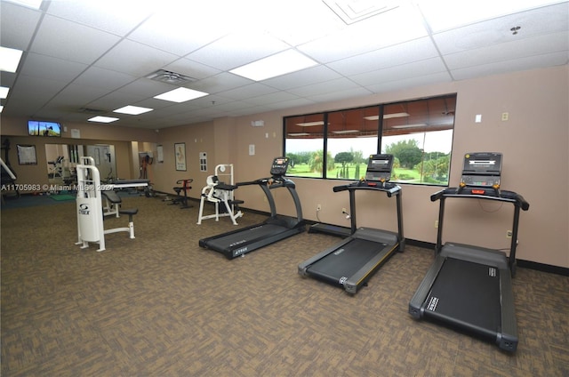 exercise room featuring a drop ceiling and dark colored carpet