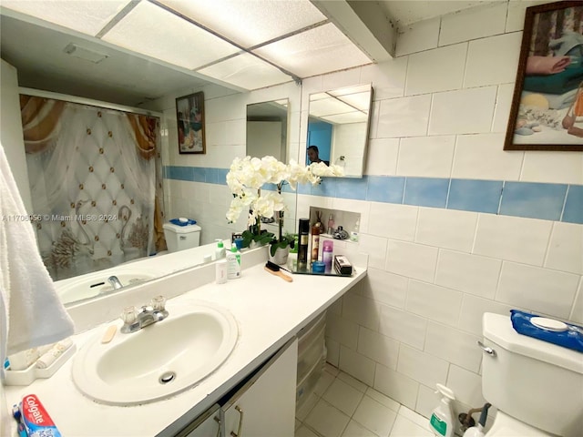 bathroom featuring a shower with curtain, tile patterned floors, toilet, vanity, and tile walls