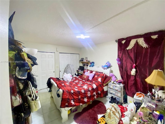 tiled bedroom with multiple closets and a textured ceiling