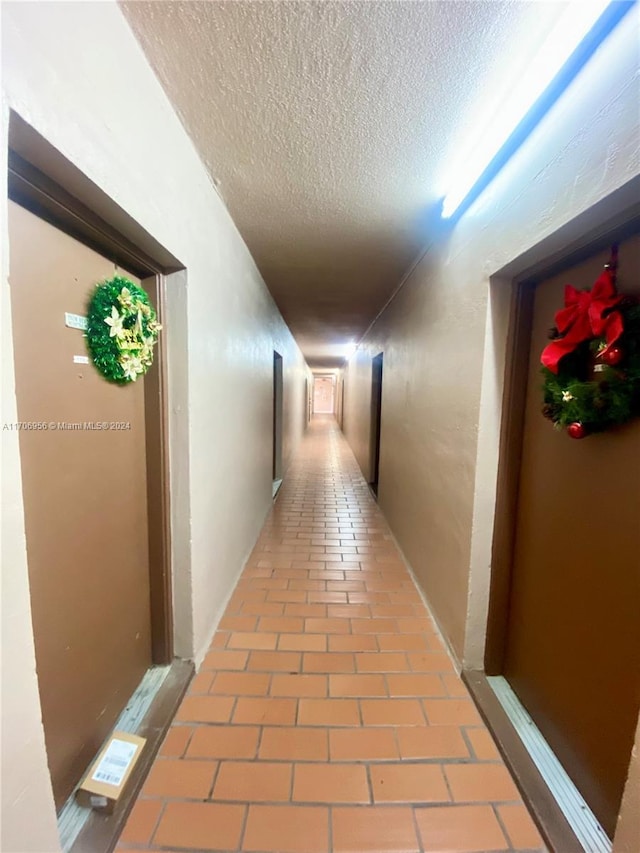 hallway featuring tile patterned floors and a textured ceiling