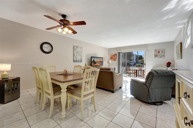 dining area with ceiling fan, light tile patterned floors, and a textured ceiling