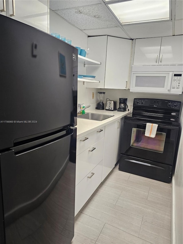 kitchen with sink, white cabinetry, a drop ceiling, and black appliances