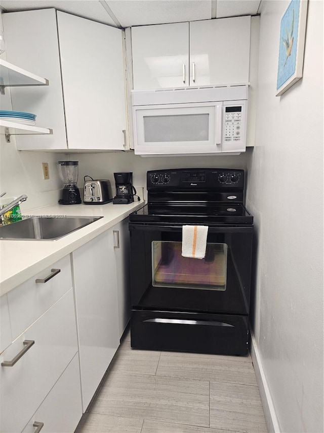 kitchen with black electric range, white cabinetry, and sink