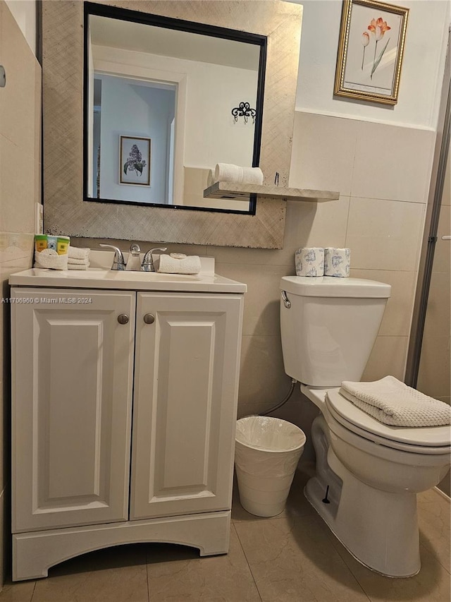 bathroom with tile patterned floors, vanity, toilet, and tile walls