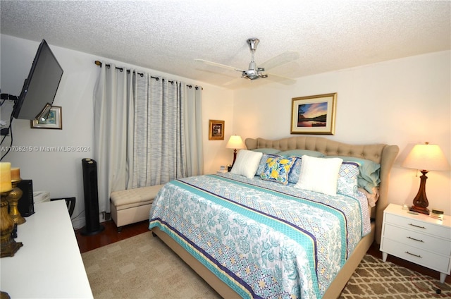 bedroom with hardwood / wood-style flooring, ceiling fan, and a textured ceiling